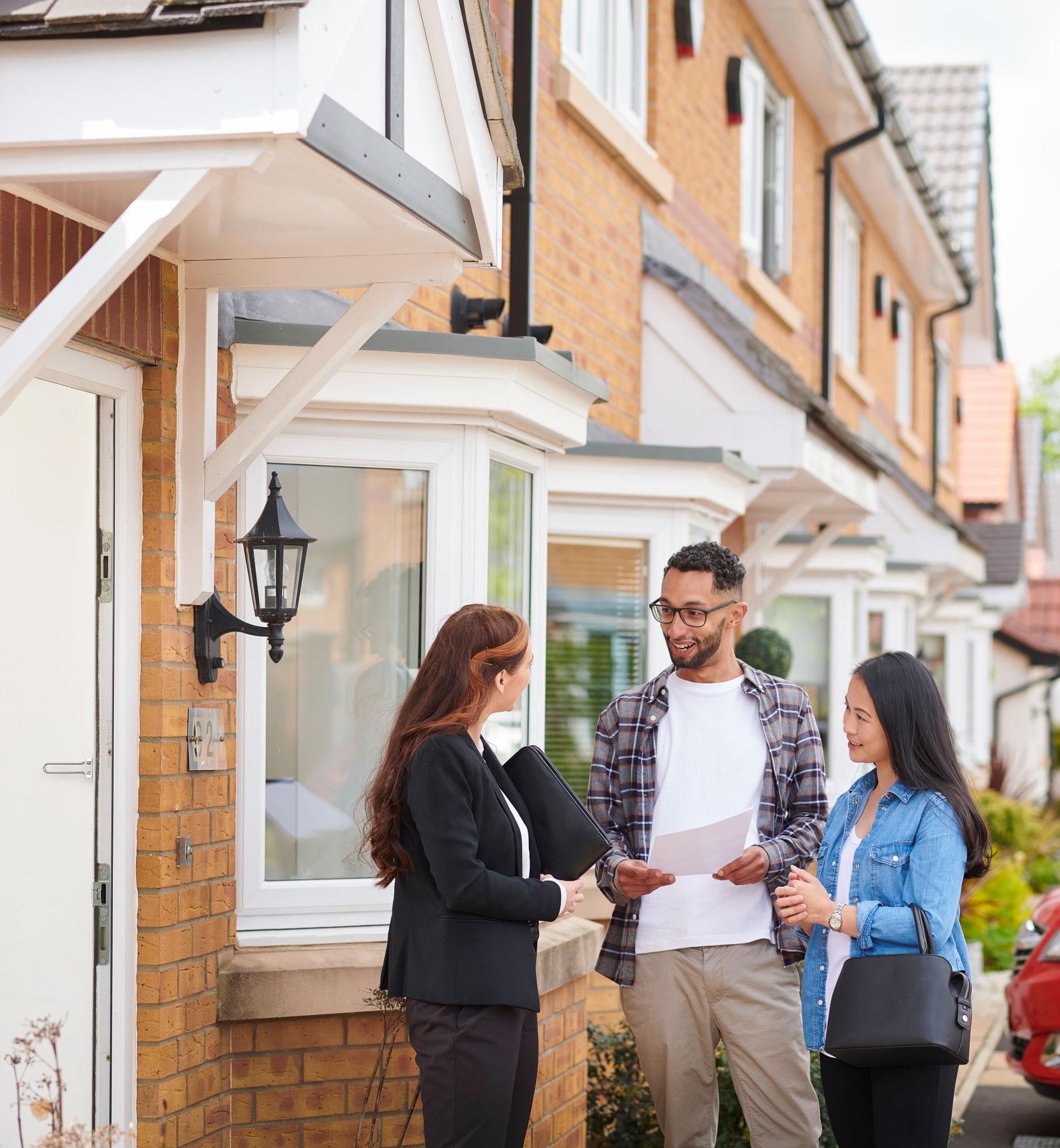 Couple outside their new home after completing their property purchase